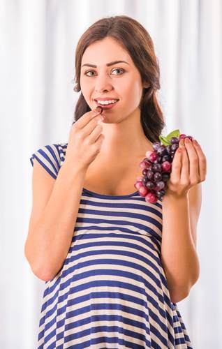 امرأة حامل تتناول العنب